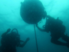 Mine Warfare; Image of two scuba divers underwater interacting with an circular mine