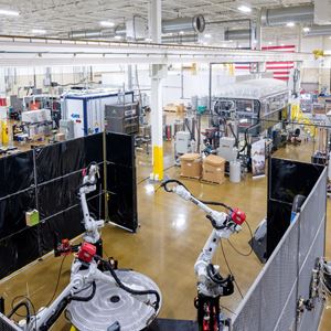 Image of the Manufacturing Demonstration Facility in Knoxville, TN which shows large ware-house facility with numerous large robotic-like machines. The floor is a light colored wood and the ceiling is while with bright long lights.   