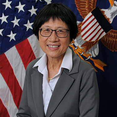 Image of Heidi Shyu. Shyu sits before an American Flag wearing a gray blazer and white button down. She has glasses and dark hair and is smiling with her teeth showing. 